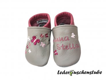 Lederpuschen in steingrau-altrosa; links 2 Schmetterlinge (bordeauxe-rosa-creme) Namen (altrosa) und rechts Stickerei 9 Schmetterlinge (bordeauxe-rosa-altrosa-creme) 